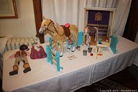 Wide view of the entire stable set laid out on a table. Includes both horses, stable, corral fence, riding outfit and accessories.