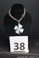 Full view of the sterling silver bracelet with four leaf clover pendant on black stand and lot number card 38.