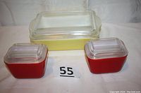 Three vintage Pyrex refrigeration storage dishes, one yellow with lid and two red with lids