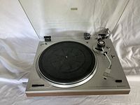 Top-down view of the Sanyo TP 105 A turntable showing the platter, tonearm, and control buttons on a white background.