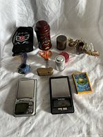 All items displayed together including art pipes, grinders, digital scales, scissors, tea, and accessories