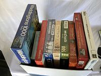 Box of 10 assorted jigsaw puzzles with visible titles and piece counts