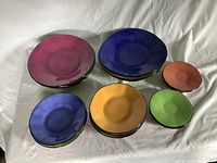 Overhead view of 16 Chintz & Co. plates of various sizes and colors including pink, blue, orange, and green, arranged by size and color groupings.