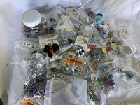 Plastic bags and containers filled with assorted costume jewelry pieces, beads, and findings