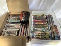 Two boxes filled with VHS movie tapes, mainly featuring Disney titles, plus a VHS head cleaner tape.