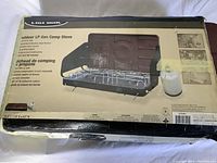 Photo of packaged Uniflame Outdoor LP Gas Camp Stove showing the box with product image and specifications.