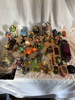Overview of assorted toys laid on cloth including figures, toy vehicles, basketball, and microscope