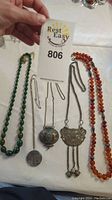 Overview of the four necklaces showing green beads, amber beads, and two silver pendants.