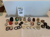 Full view of all 27 rings displayed in rows showing variety of styles and colors including metallic, enamel, beaded and rhinestone accented pieces.