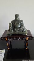 Front view of jade Buddha statue seated on wooden stand