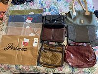 Overview photo showing five new pashminas in packaging and six assorted purses on floral bedspread.