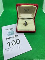 Ring displayed in red velvet Unity Creation box with auction lot card