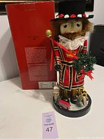 Full view of the nutcracker with its original box, showing the red box with Bombay branding, the nutcracker figurine standing on a round base with London landmarks.