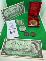 Full lot showing two Canadian Centennial one dollar bills, two smaller coins, one larger commemorative coin sealed in plastic, and a gold-tone medallion with chain in a display box.