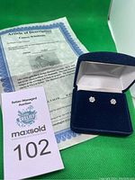 Certificate of authenticity and pair of earrings in navy blue velvet box