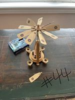 Full wooden carousel showing detached blade and included matchbox for scale