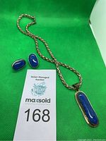 Photo showing the necklace with thick rope silver chain and elongated lapis lazuli pendant alongside matching oval lapis lazuli earrings