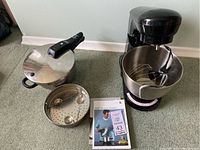MasterChef mixer with attachments and WMF pressure cooker with lid, steamer basket, and user manual on floor