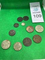 Overview photo of 10 old coins including English pennies, half crowns, and Canadian crowns on a green surface.