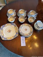 Full set displayed on table showing cups on saucers, stack of dessert plates, cream and sugar set, and cake plate.