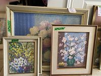 Photo showing all three framed floral oil paintings stacked together, with dimension notes.