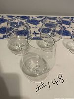 Five vintage crystal brandy snifters arranged on a table, showing four different etched 'Ponytail Girl' designs by Raymond Peynet.