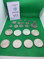 Four Morgan silver dollars front row, four Peace silver dollars in second row, assorted smaller coins behind