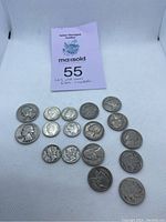 Overview of 17 older U.S. coins arranged on white background with auction number card behind