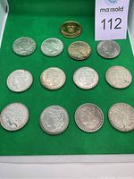 Multiple silver dollars, Eisenhower dollar, and brass medal on green felt
