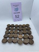 Most of the vintage US pennies laid out in rows on a white background with a MaxSold auction lot number and note indicating $1.50 worth and dated from 1940s to 1960s.