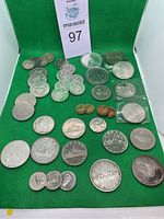 Overview of all coins on green felt background including various silver and copper coins