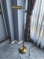 Full view of the vintage brass floor lamp showing the entire lamp from base to top with cord on the floor.