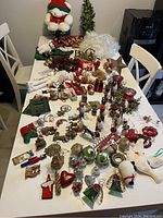 Wide angle of the full vintage Christmas lot across a dining table showing a variety of plush, figurines, garlands, ornaments and holiday decorations.
