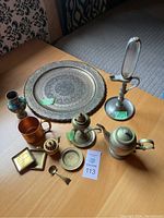 Full lot overview displaying all vintage metal decor items including tray, lamps, teapot, cup, spoon, and framed pieces on a wood table