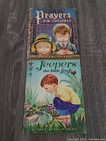 Photo of two vintage children's books on wooden floor, titles Prayers For Children and Jeepers The Little Frog.
