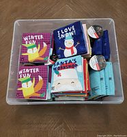 Large plastic bin containing 22 small soft fabric children's books with winter and holiday-themed covers