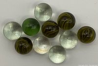 Ten glass marbles shown in a group including multiple swirl pattern marbles, clear marbles, and one green marble.