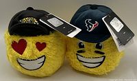 Photo of two new NFL collectible emoji plush toys. One wears a black Jacksonville Jaguars cap and the other a dark blue Houston Texans cap, both have tags attached.