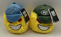 Lot of 2 NFL collectible plush toys featuring Detroit Lions and New York Jets, each with a yellow smiling face and team logo caps.