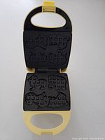 The waffle maker open showing the animal circus shaped non-stick waffle/mold plates inside.