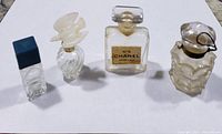 Four vintage mini perfume bottles on a white background: one Chanel No. 5 square bottle and three assorted styles.