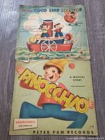 Photo showing two vintage Disney Peter Pan children's records: 'On The Good Ship Lollipop' and 'Pinocchio: A Musical Story'. Both have illustrated covers with minor wear.