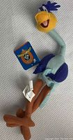 Full view of the vintage Road Runner plush showing multicolor fabric, facial details, and attached tags.