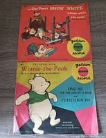 Photo of two vintage 78RPM Golden Records: one Snow White record sleeve with Disney characters and the other Winnie The Pooh record sleeve with Pooh bear illustration.
