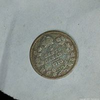 Reverse side of the 1910 Canadian 5 cent coin showing denomination, country and year with maple leaf wreath design.