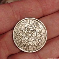 Reverse side of the 1956 UK 2 Shilling coin with Tudor rose and surrounding floral designs and denomination text.