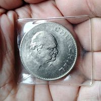 Close-up of the 1965 Winston Churchill crown coin showing Churchill's profile and the inscription 'CHURCHILL' on the coin's face, housed in plastic holder.