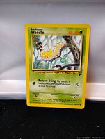 Front of Weedle Pokemon card from Base Set 2, showing artwork, HP and attack details
