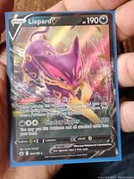Front view of the Liepard V full art Pokemon card held in hand, showing its holographic design and details.