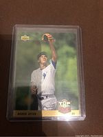Front view of the Derek Jeter rookie card showing the player fielding with a glove worn on the left hand in New York Yankees pinstripe uniform, with the Upper Deck and Top Prospect 93 logos visible.